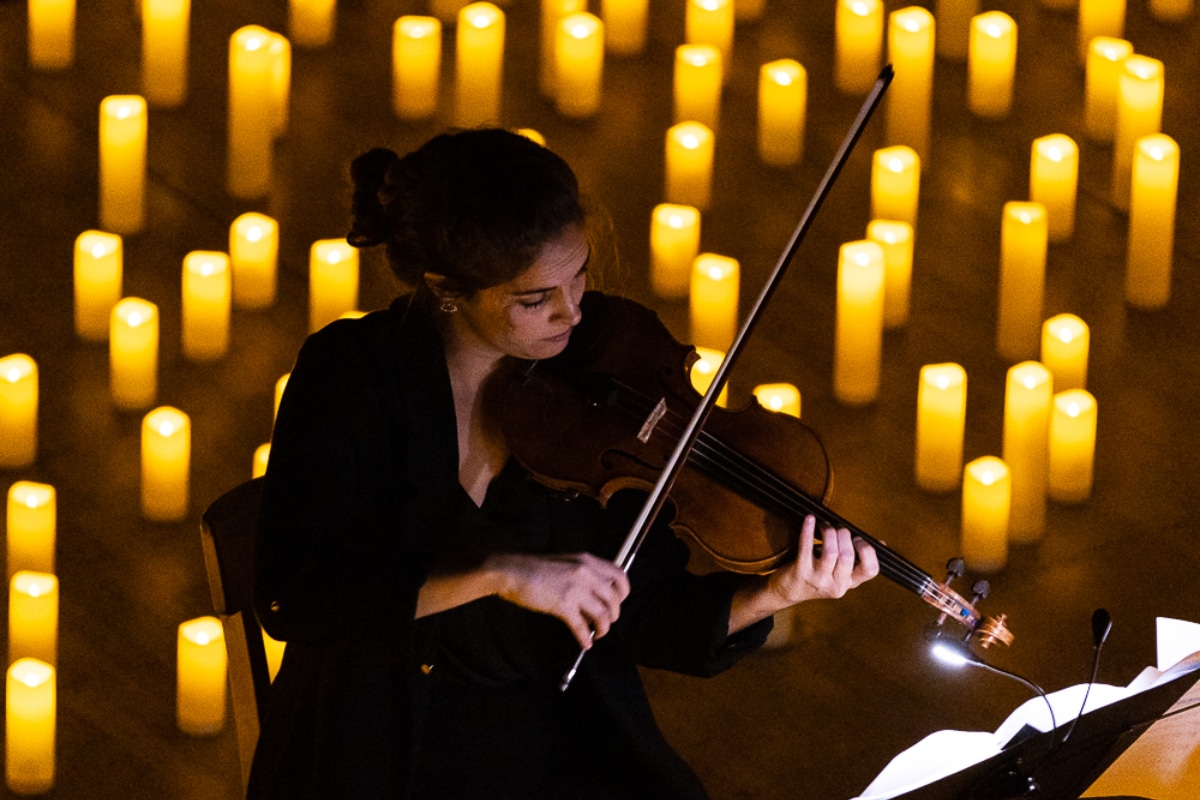 Musician playing the violin on stage surrounded by candles