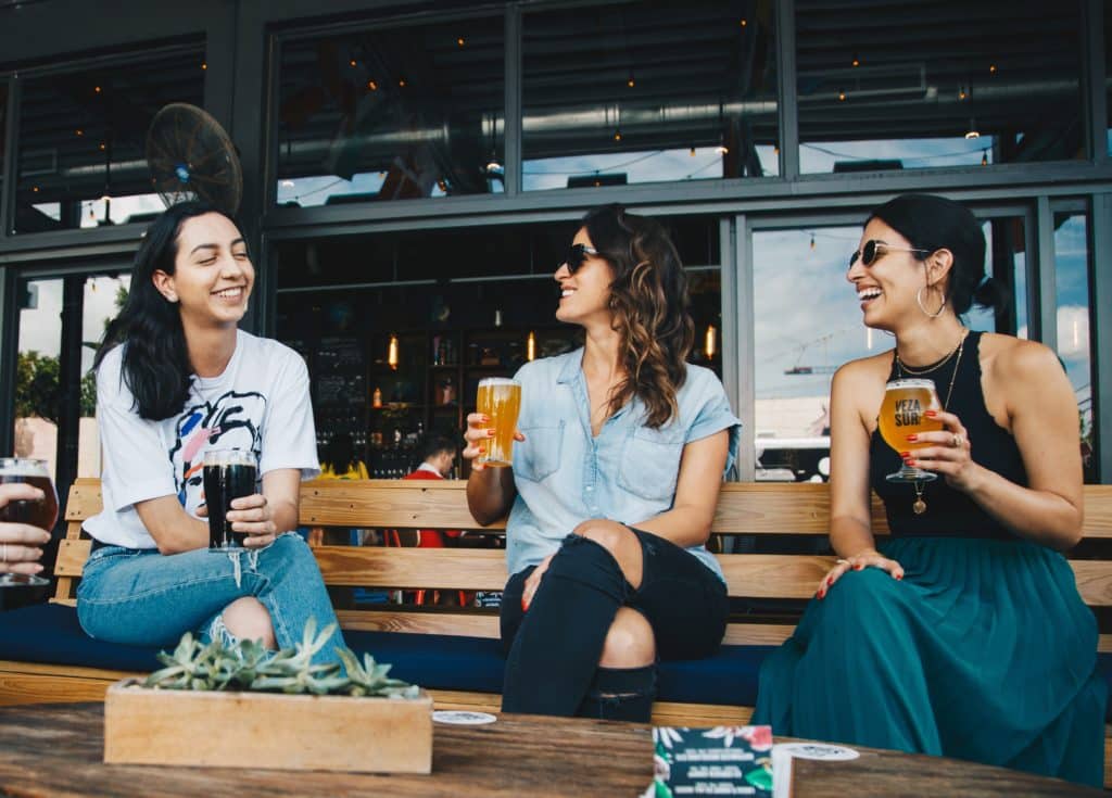 Three women drinking beer at bar