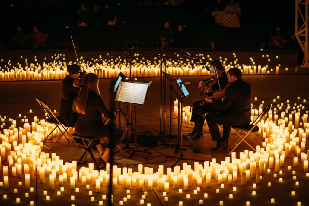 A string quartet performing in a circle surrounded by candles.